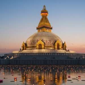 A majestic and intricately detailed depiction of the ancient Dharmarajika Stupa, set against a serene twilight sky with hues of soft blue, pale pink, and warm gold. The stupa is adorned with traditional Indian patterns and motifs, highlighted by a gentle glow emanating from its base and apex. In the foreground, a tranquil water surface reflects the stupa, surrounded by stylized lotus flowers and floating candles. The scene captures the essence of spirituality and historical significance, with soft glowing lights creating an ethereal ambiance. Indian cultural elements like mandalas are subtly incorporated into the stupa's architecture, blending heritage with a modern digital aesthetic. The overall composition is serene and inviting, evoking a sense of wonder and curiosity about the rich history of the Dharmarajika Stupa.